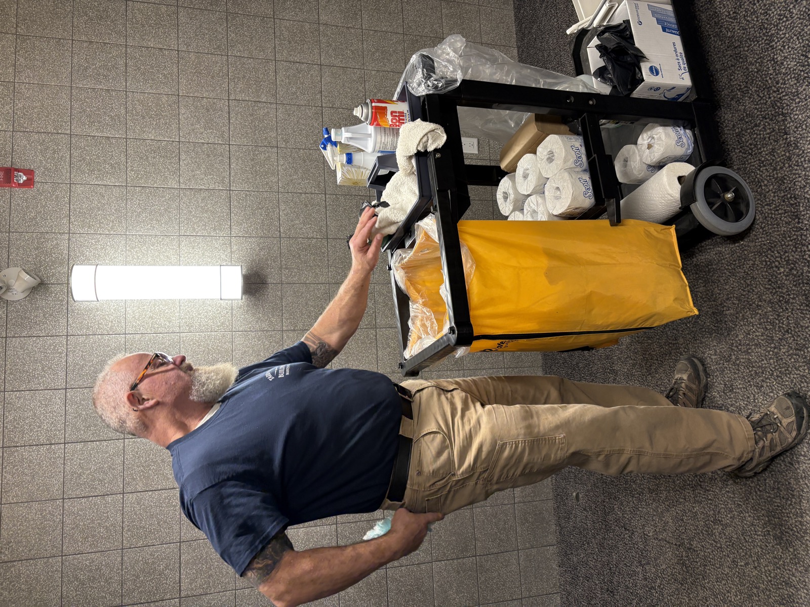 Bill Tarr restocking his fully stocked janitor cart in a facility hallway